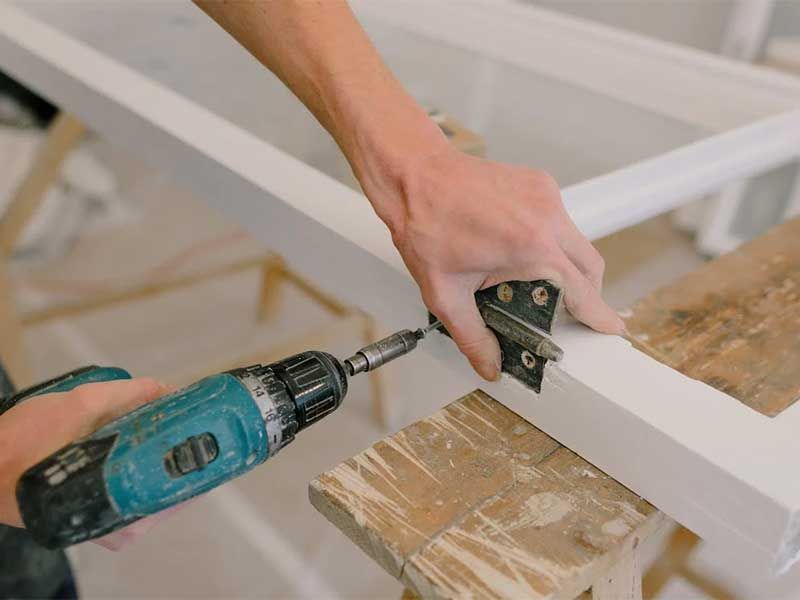 A person is using a drill on a piece of wood.