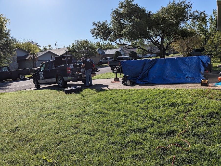 A truck is parked in the grass next to a blue tarp.