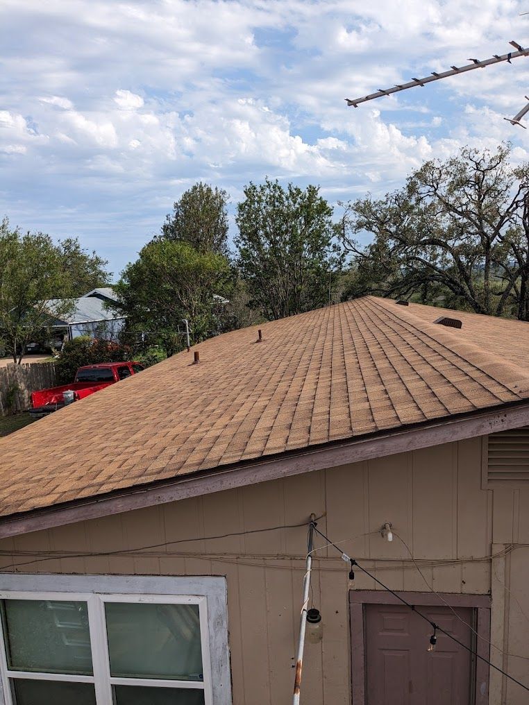 A house with a brown roof and a red truck parked in front of it.