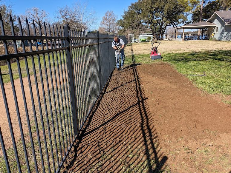 A man is plowing a path next to a fence.