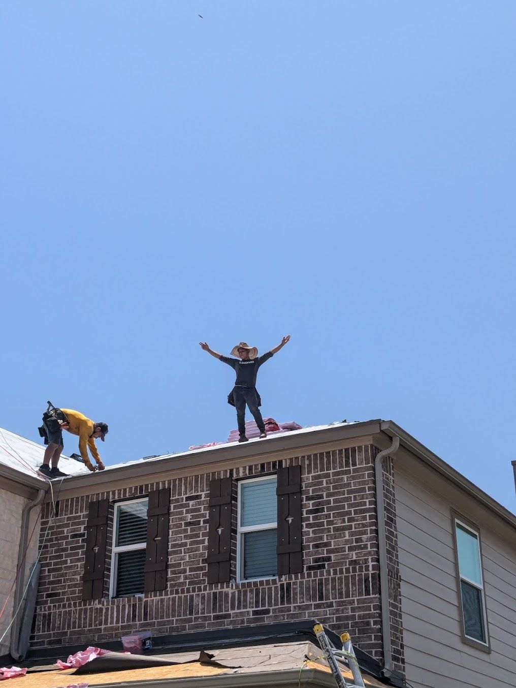 A woman is standing on the roof of a house with her arms outstretched.