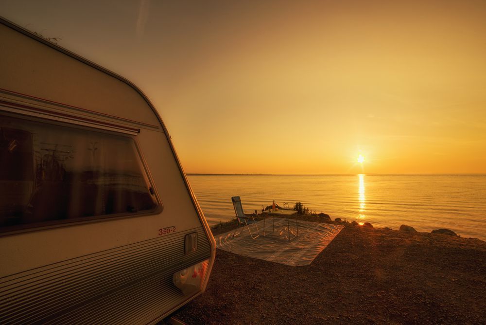 A Caravan Is Parked On The Beach At Sunset — Kingston Caravan Repairs In Lake Macquarie, NSW