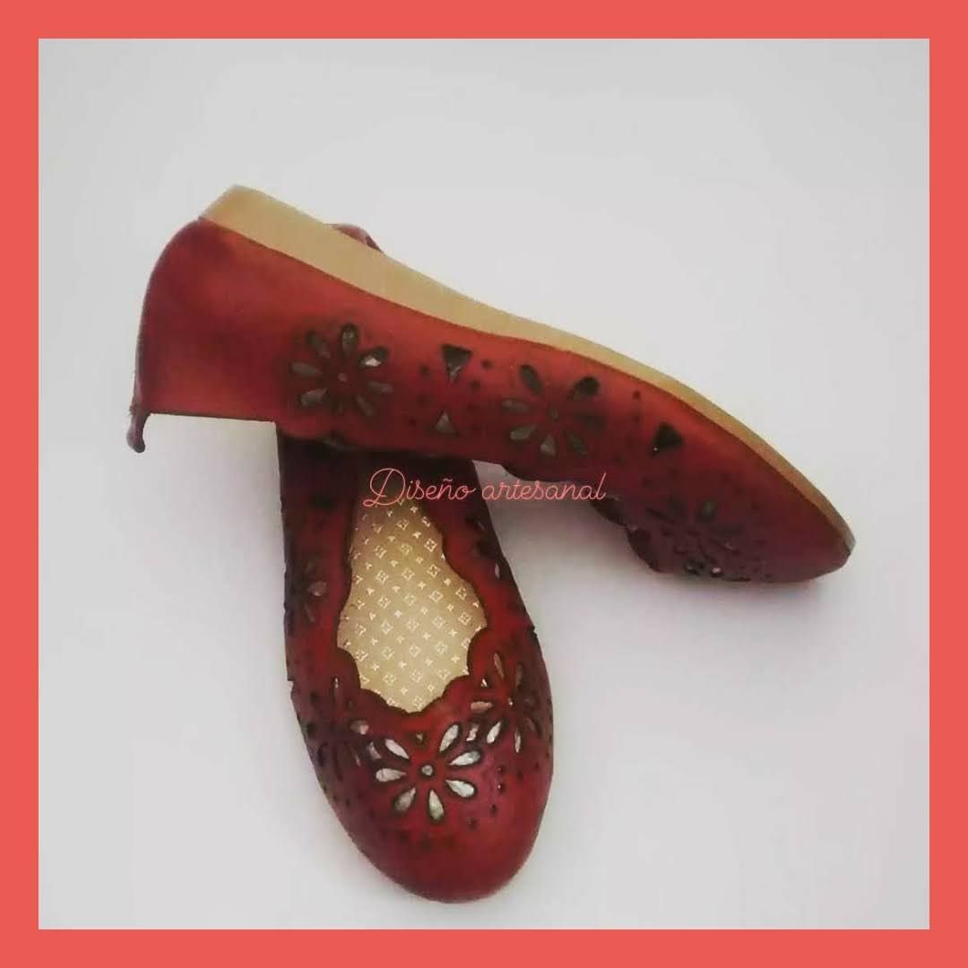 Un par de zapatos planos rojos con estampados florales cortados con láser 