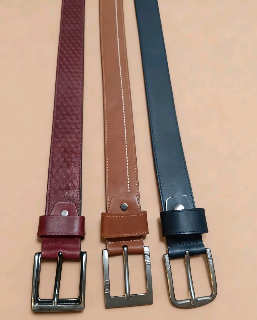 Tres cinturones colocados uno al lado del otro, de color rojo oscuro, marrón claro y azul oscuro
