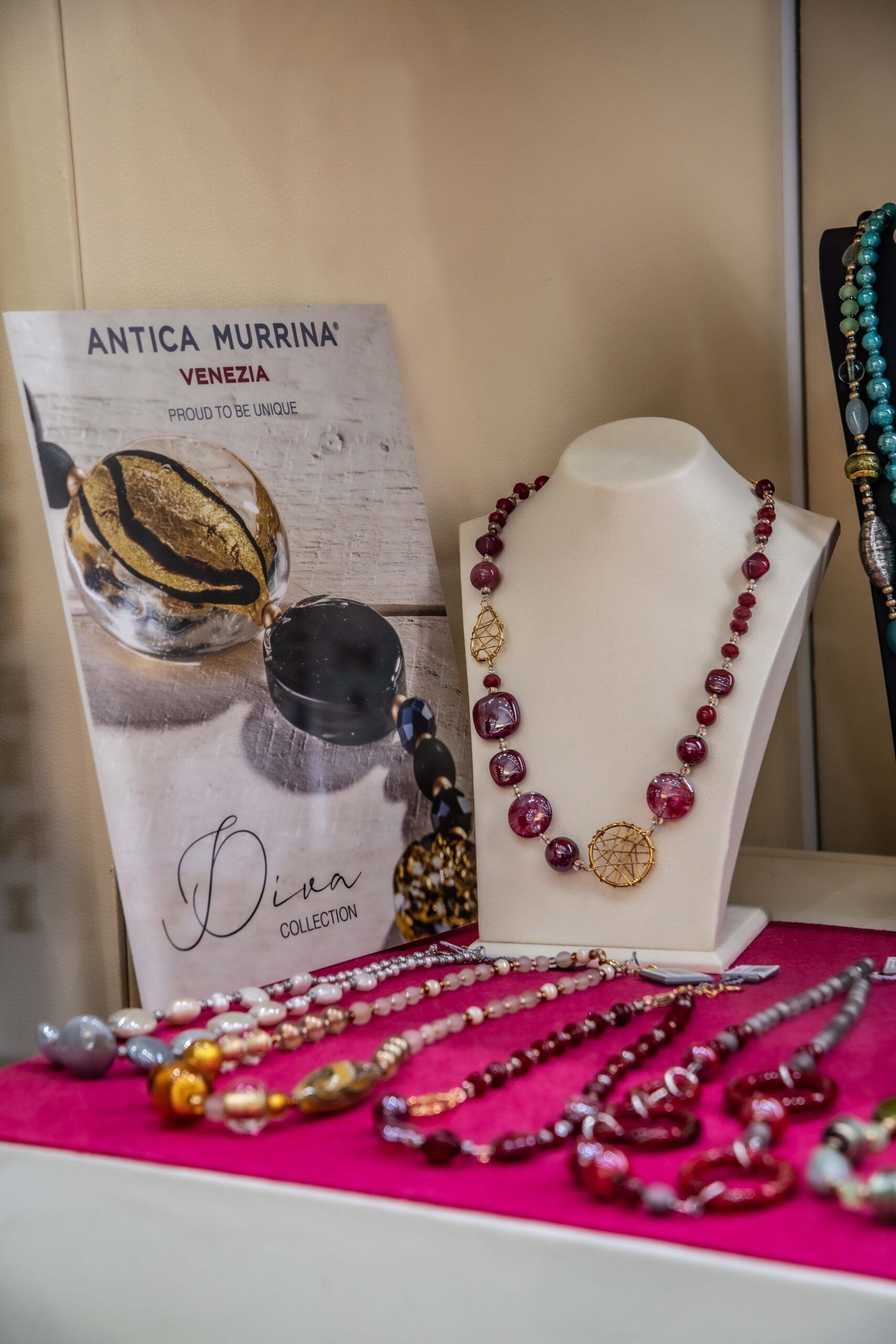 Un'esposizione di collane e braccialetti su un tavolo rosa.