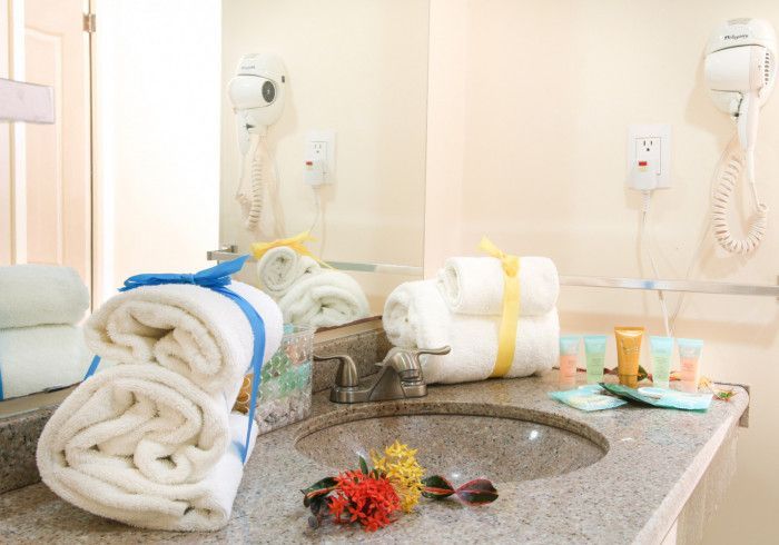 Bathroom with towels, sink, mirror, and toiletries. Towels are tied with blue and yellow ribbons.
