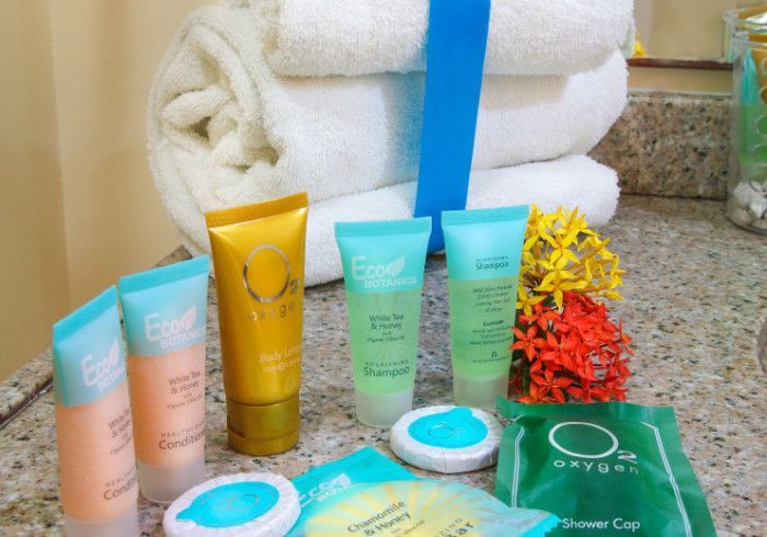 Bathroom toiletries: towels, bottles of shampoo and lotion, soap, and a shower cap arranged on a countertop.