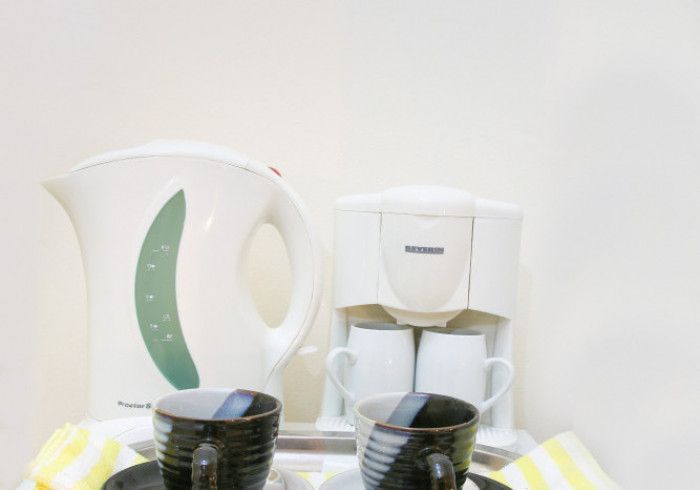 Electric kettle, coffee maker, and two cups on a tray.