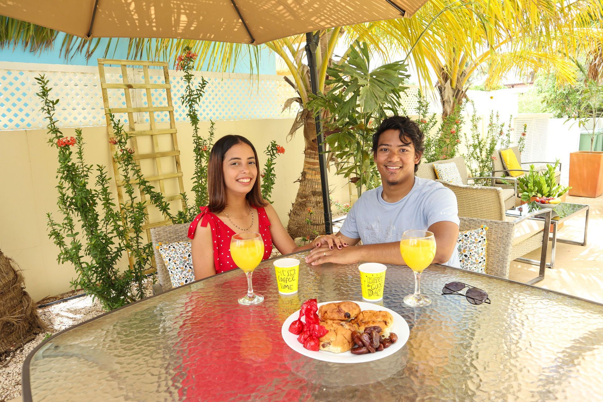 Couple at outdoor table with drinks and food, smiling.