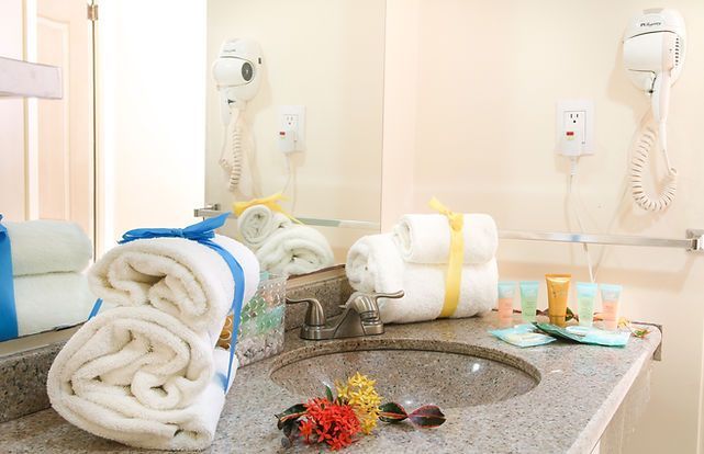 Bathroom with towels, sink, mirror, toiletries, and hairdryer.