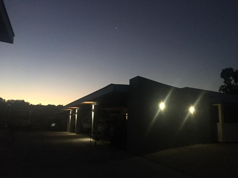 A House is Lit Up at Night With a Sunset in the Background — AH Electrical in West Ballina, NSW