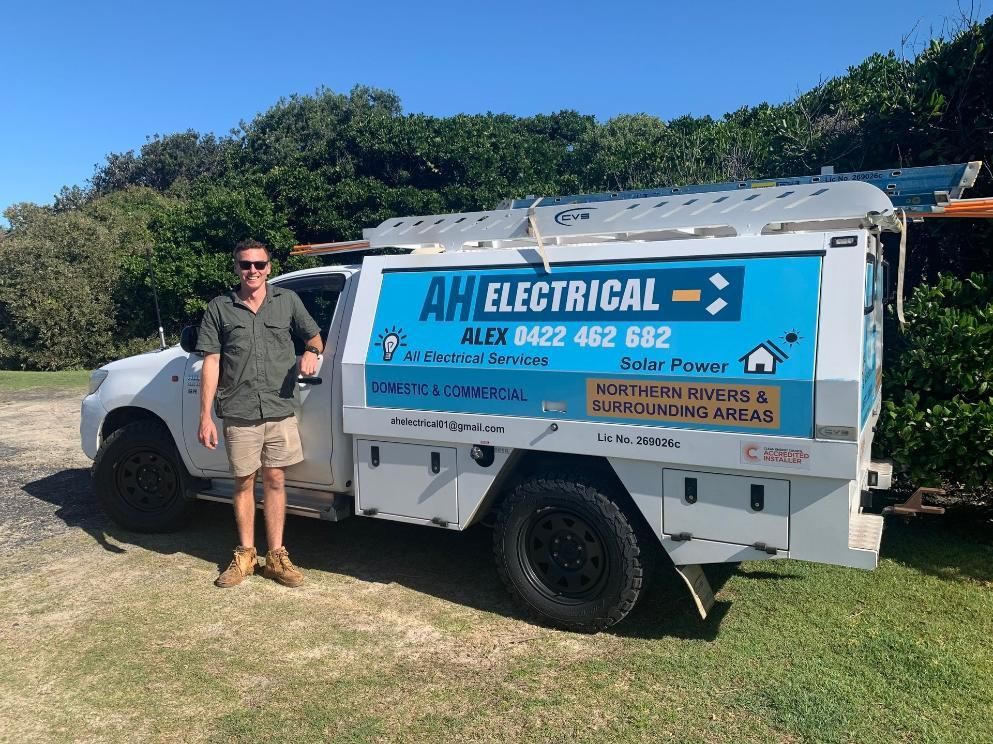 A Man Is Standing In Front Of An Electrical Truck — AH Electrical in Kyogle, NSW