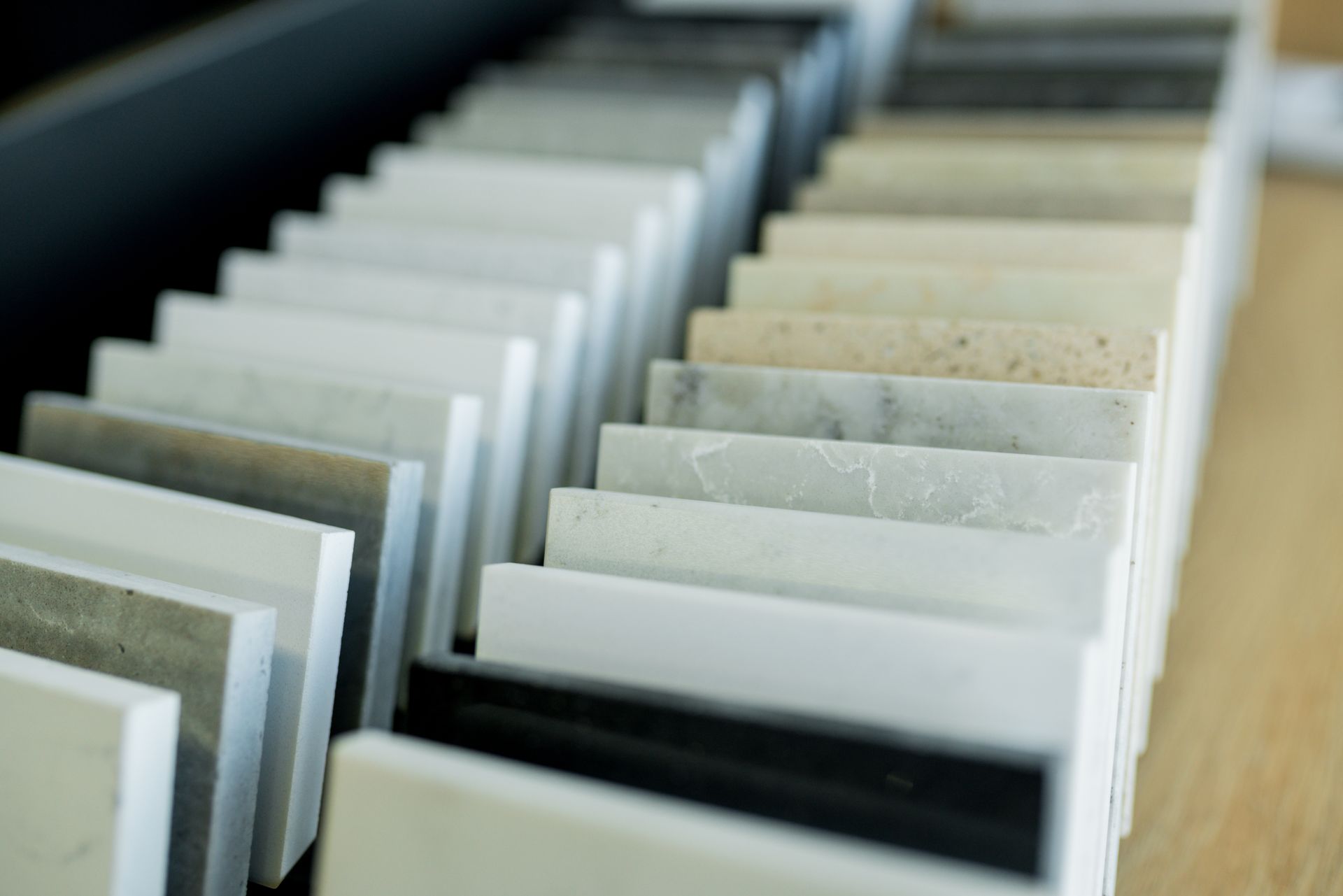 An angled close-up of a sample rack featuring various stone, quartz, and laminate countertop material swatches.