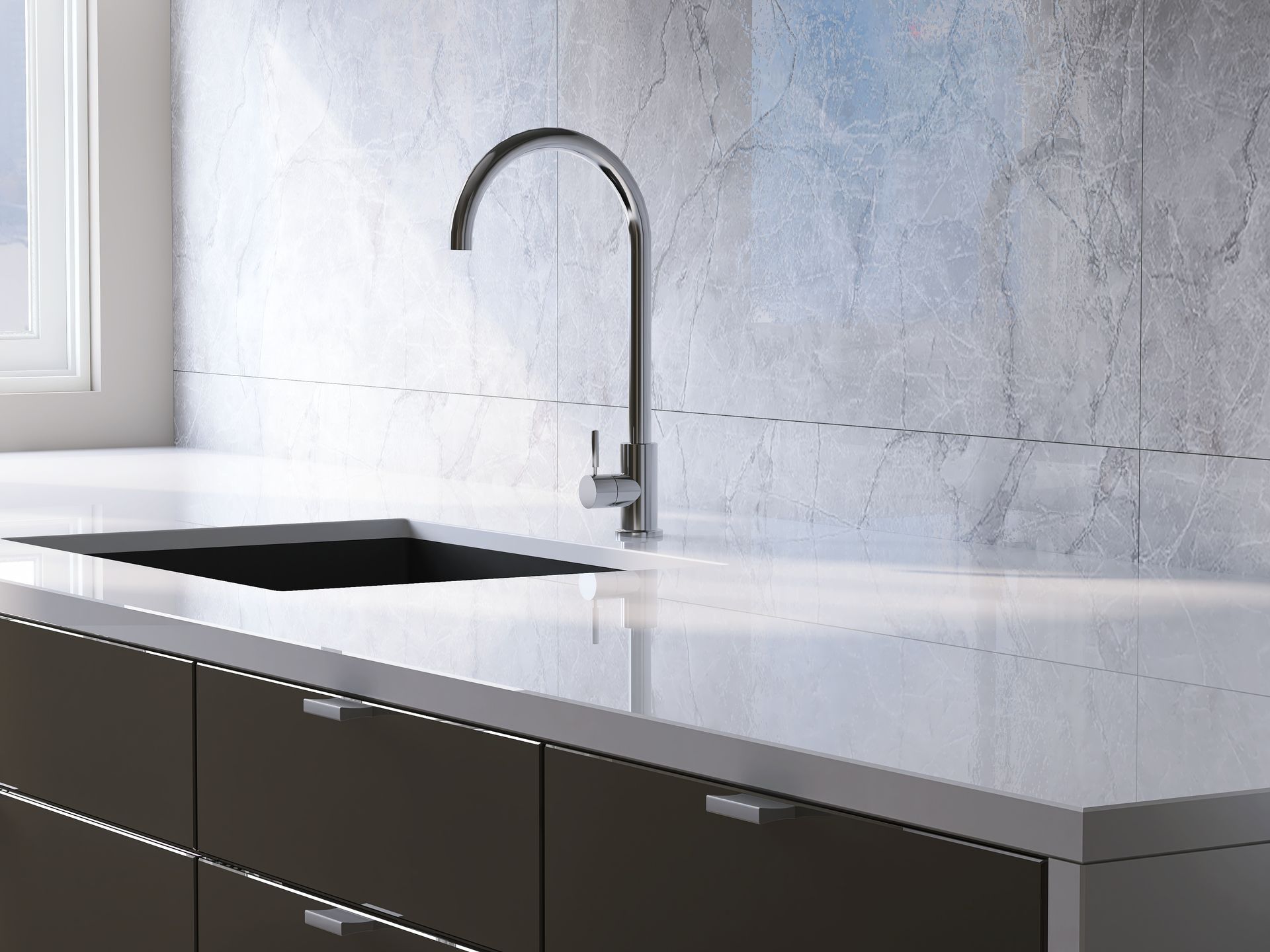 A sleek, modern kitchen scene featuring a dark sink, a tall silver faucet, and a white countertop against a marble wall.