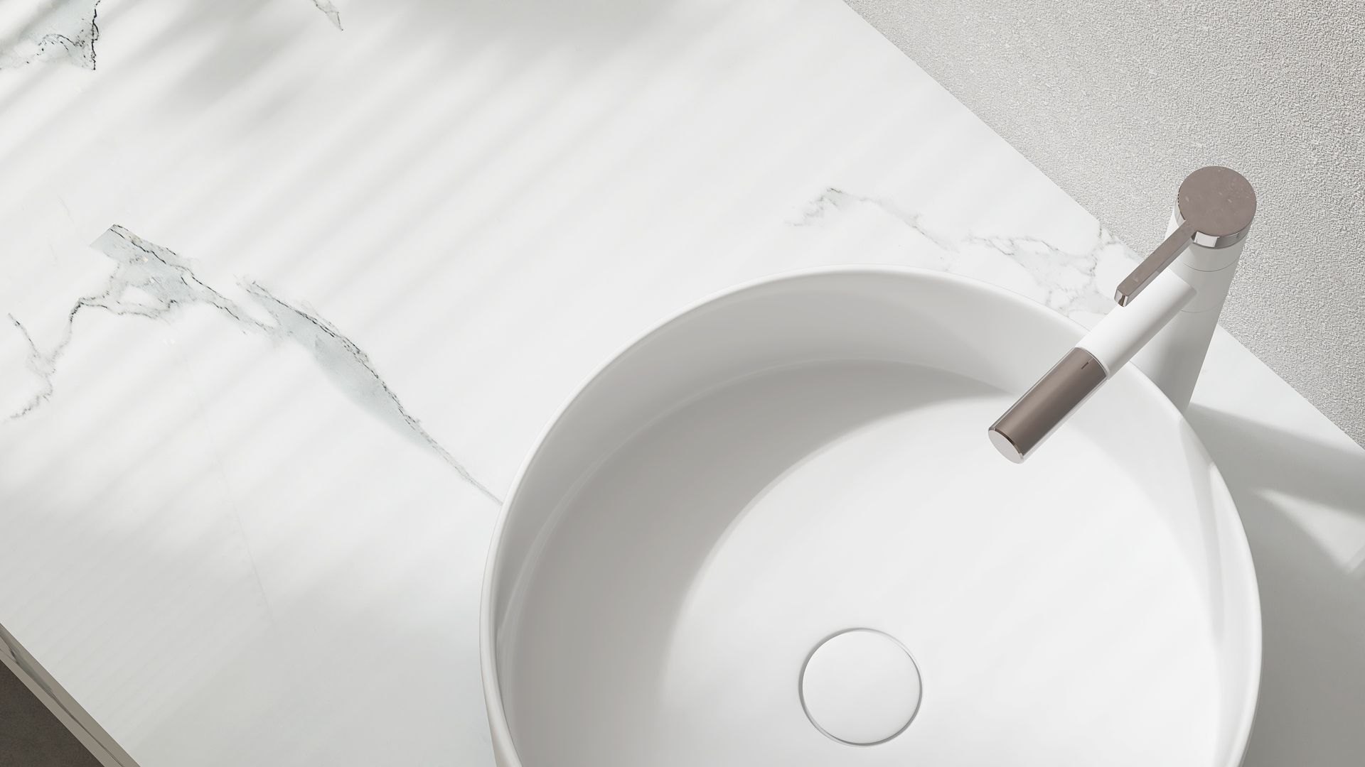 A modern white marble bathroom vanity with a sleek, minimalist vessel sink and a matte metallic faucet.
