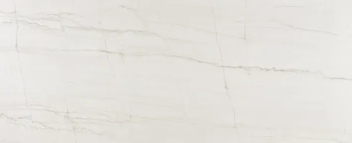 A close-up view of white marble stone with faint, soft grey veining throughout the smooth, polished surface.
