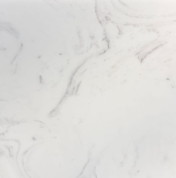 A close-up view of white marble stone with faint, soft grey veining throughout the smooth, polished surface.