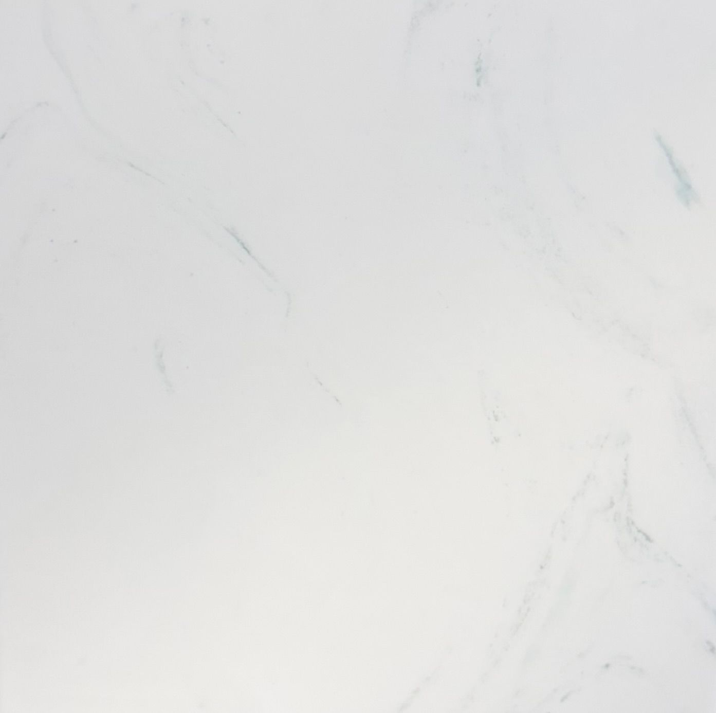 A close-up view of white marble stone with faint, soft grey veining throughout the smooth, polished surface.