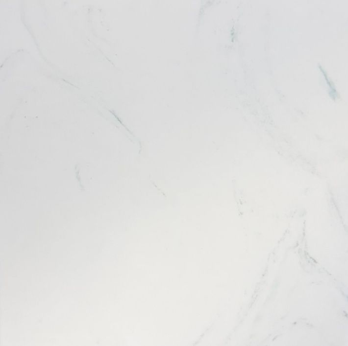 A close-up view of white marble stone with faint, soft grey veining throughout the smooth, polished surface.