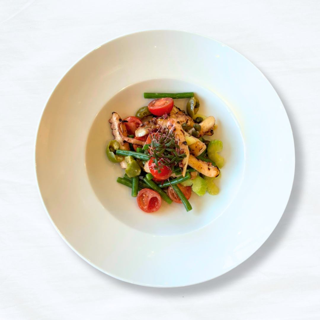 A white plate of Grilled Octopus on a white tablecloth-covered table. 
