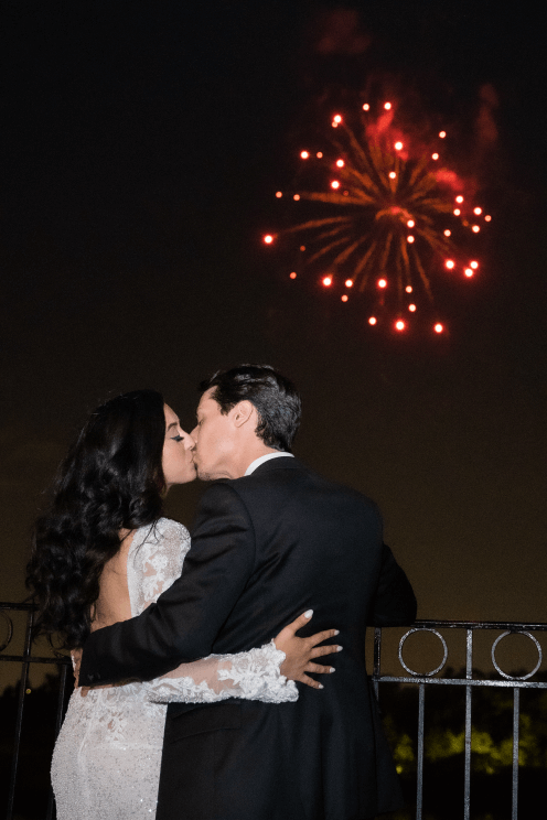 Married couple kissing with fireworks in the background