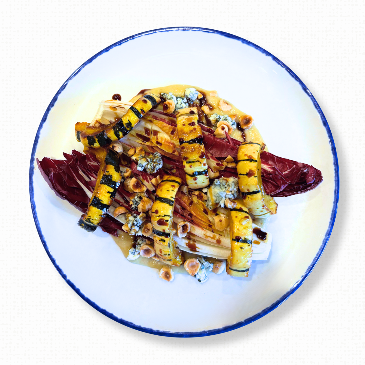 A white plate of Treviso & Delicata Squash on a white tablecloth-covered table. 