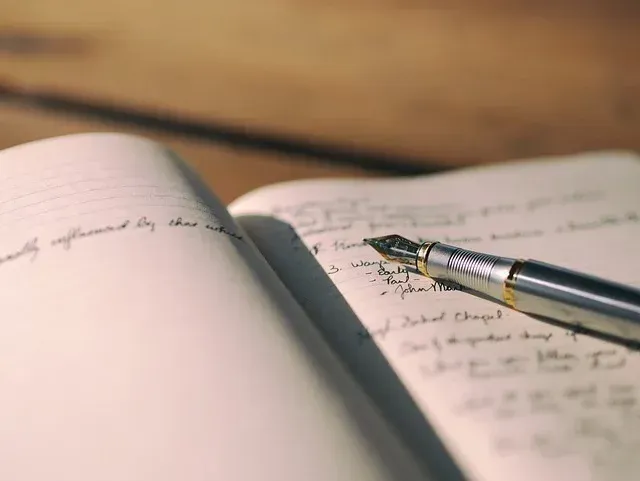 Open notebook with handwritten notes and a fountain pen on a wooden table