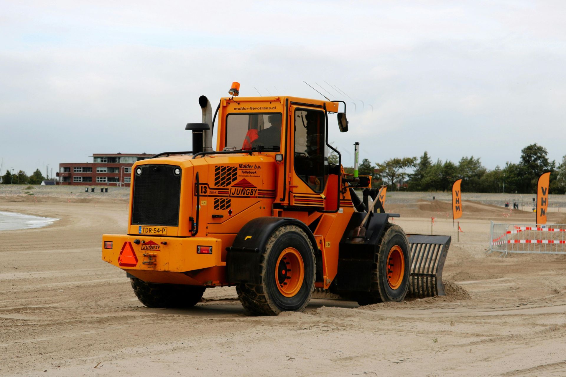 Orange beach cleaner machine on a sandy beach.