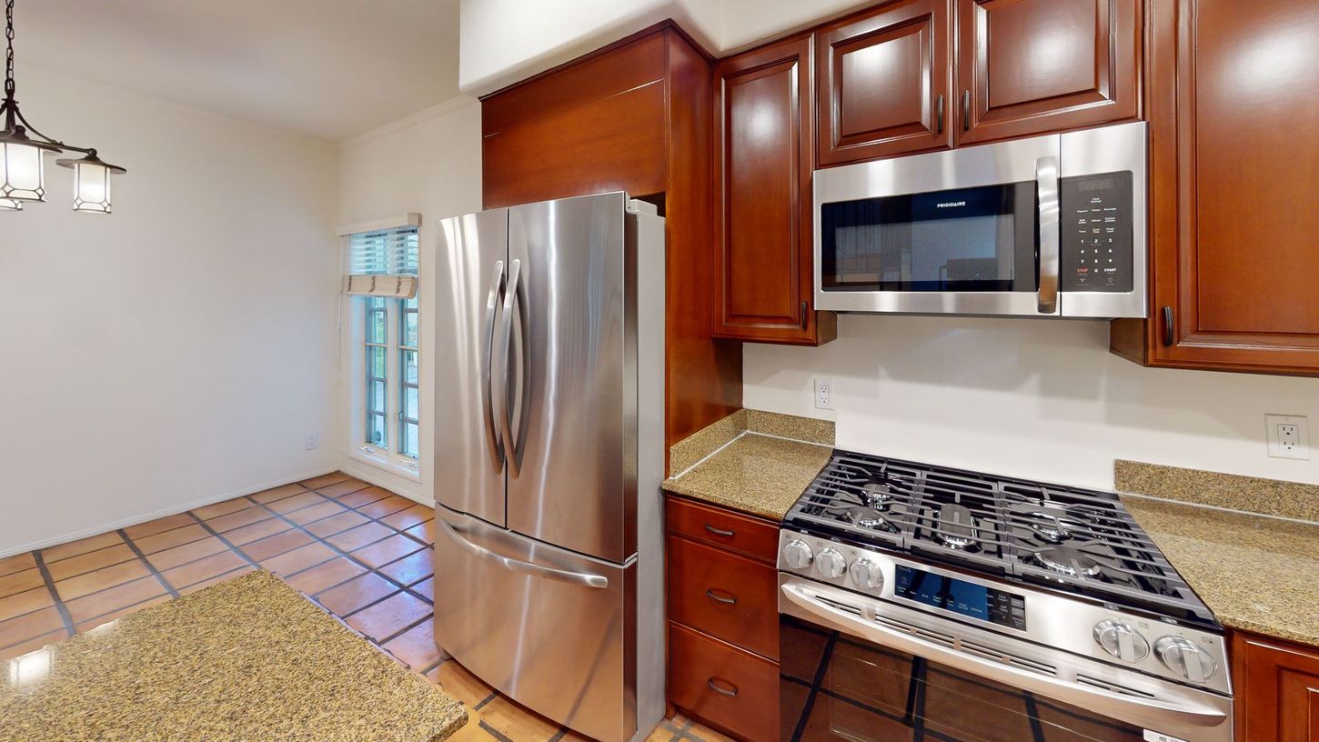 Kitchen with stainless steel appliances, brown cabinets, and a tile floor.
