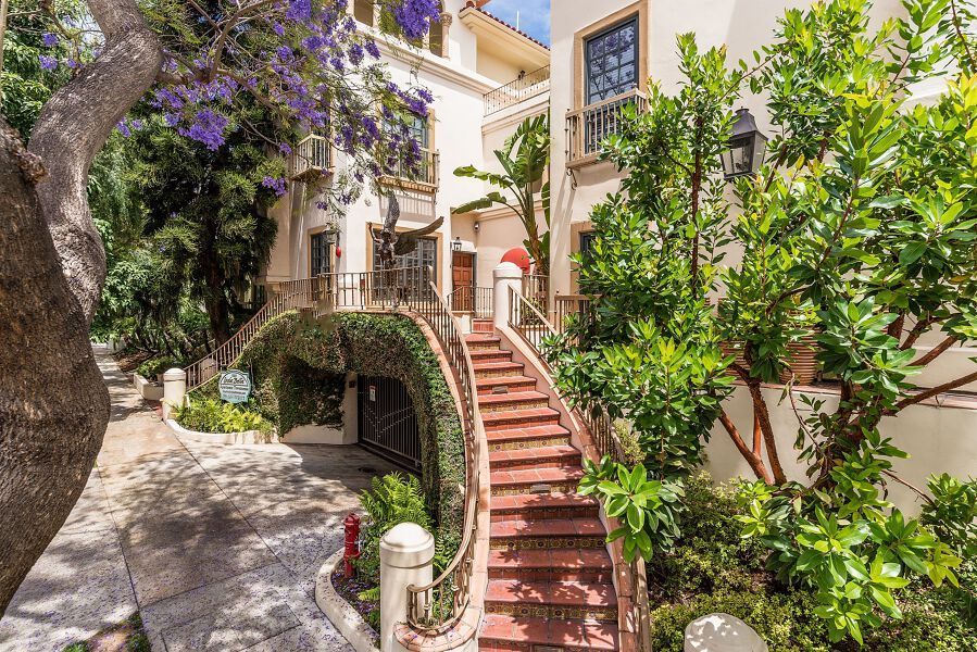 Building with red staircases, green foliage, and flowering purple trees.