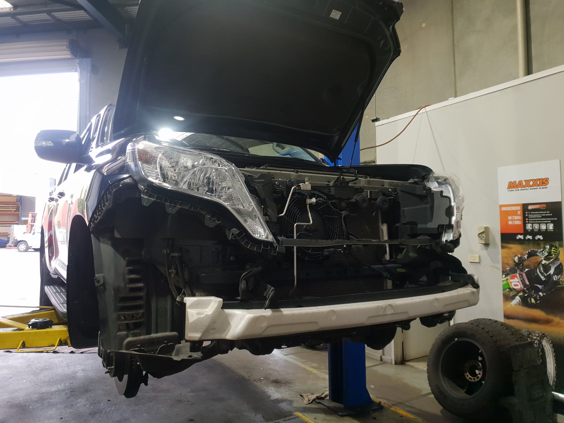 Damaged SUV in A Repair Shop, Front End Crushed, Hood Open, Tire Removed — Autoplus Picton in Picton, NSW