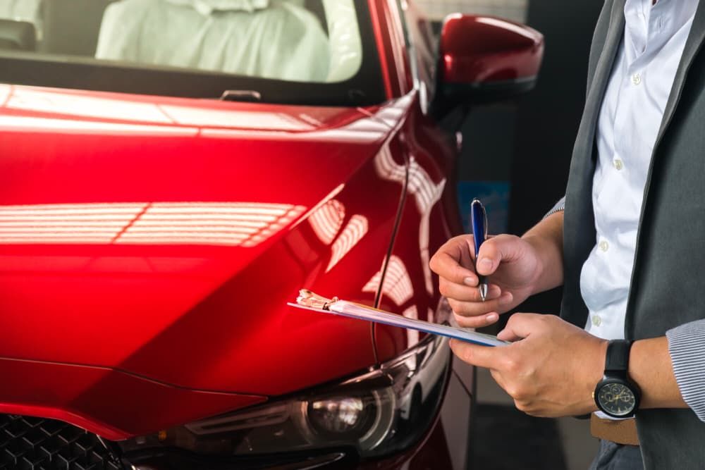 Person in Suit Inspecting a Red Car Holding Clipboard — Autoplus Picton in Picton, NSW