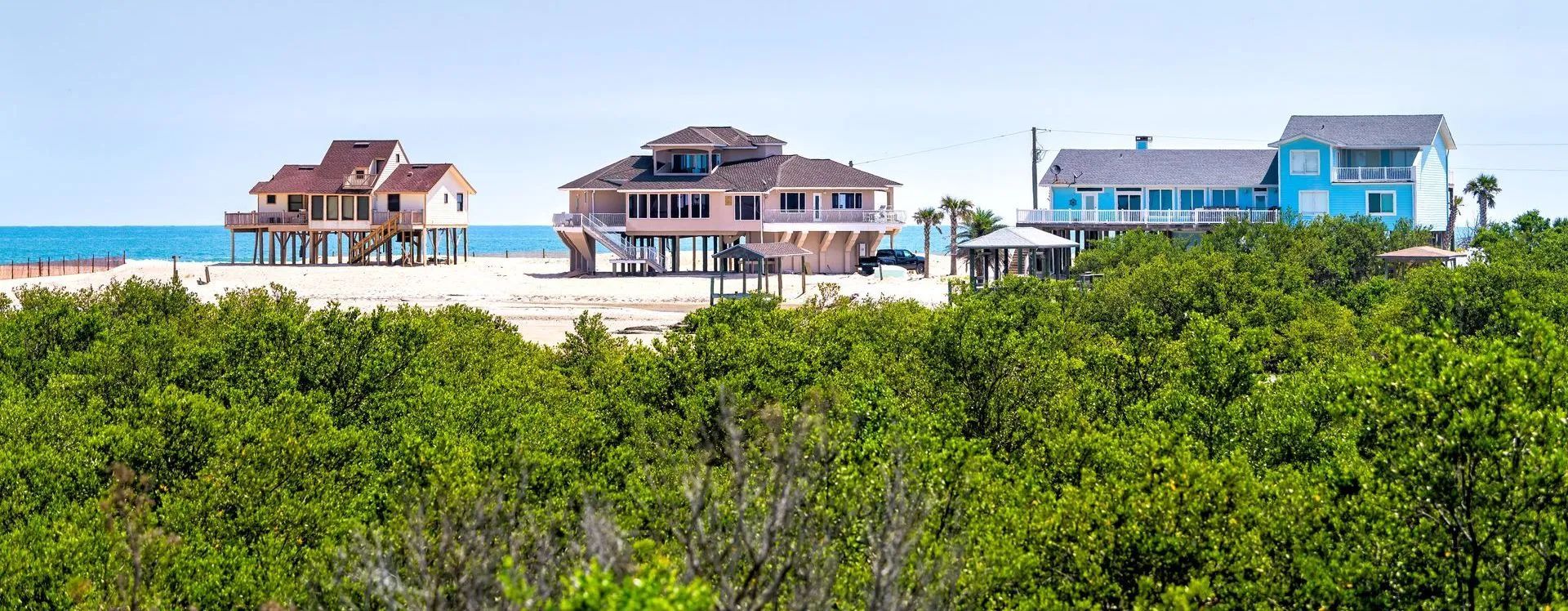 A group of houses are sitting on top of a hill next to a beach.