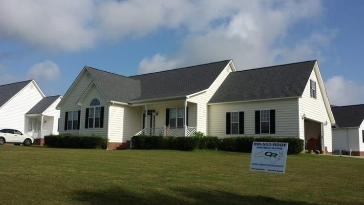 A cream-colored house with a dark gray roof and black shutters. A 