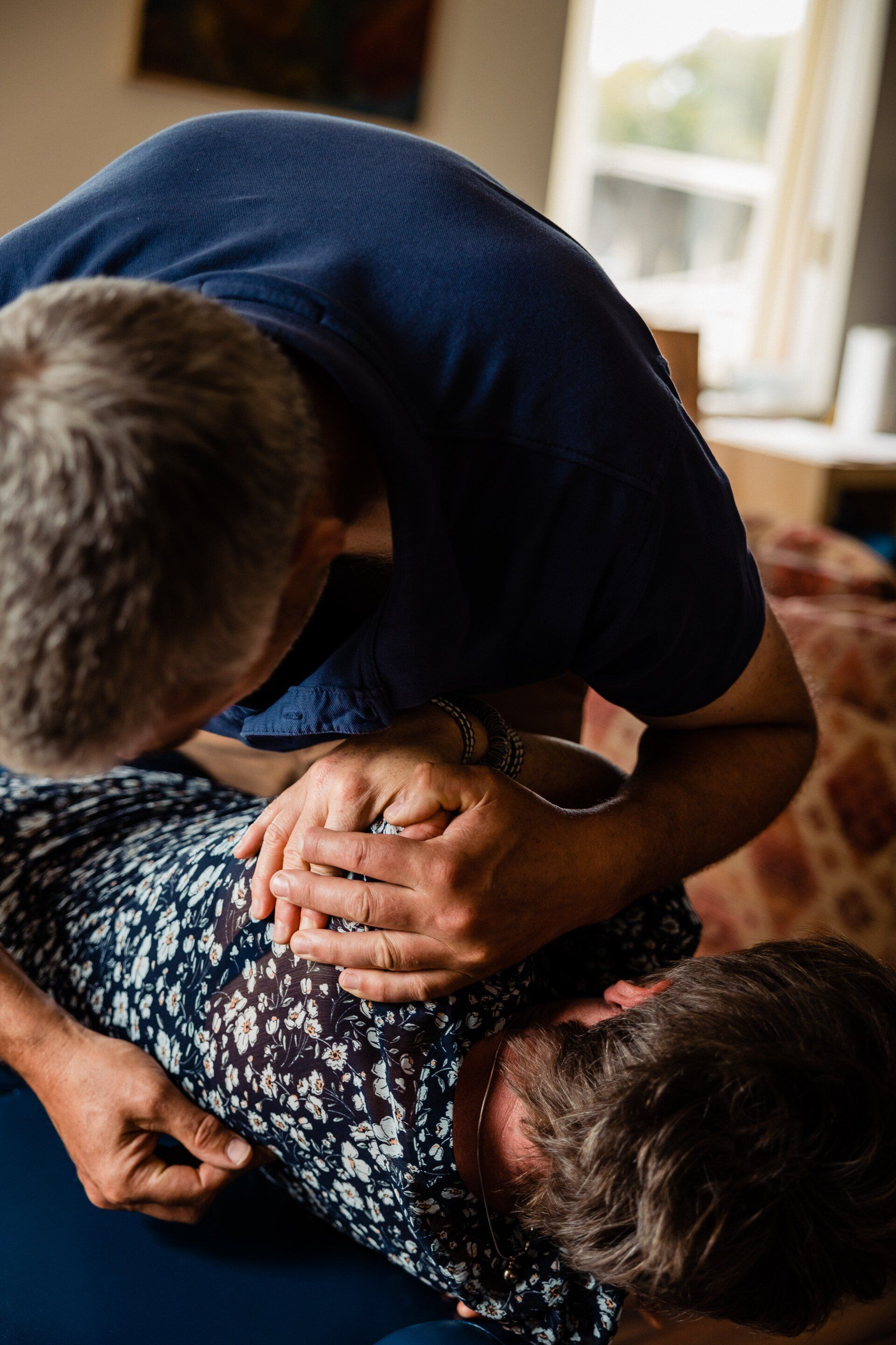 a man is holding another man 's hand while laying on a couch .