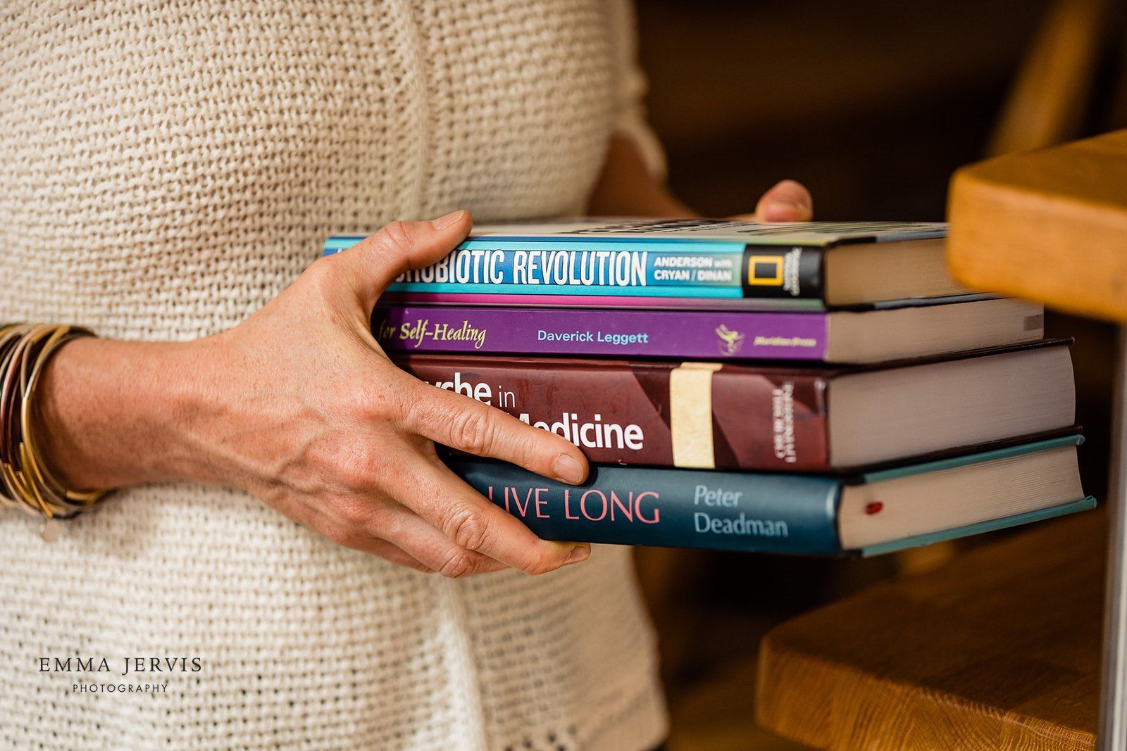 a woman is holding a stack of books in her hands .