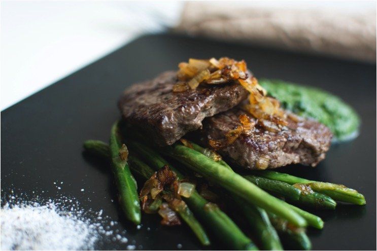 a close up of a plate of food with green beans and meat