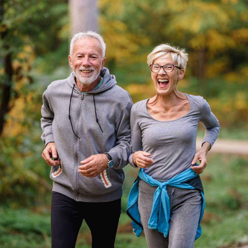 a man and a woman are jogging together in a park .