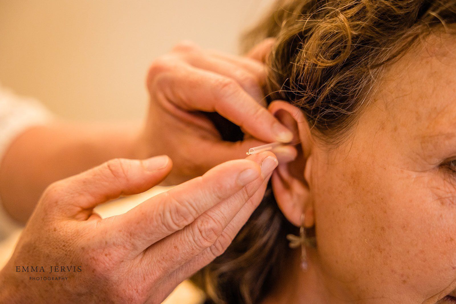 a woman is getting a hearing aid put in her ear .