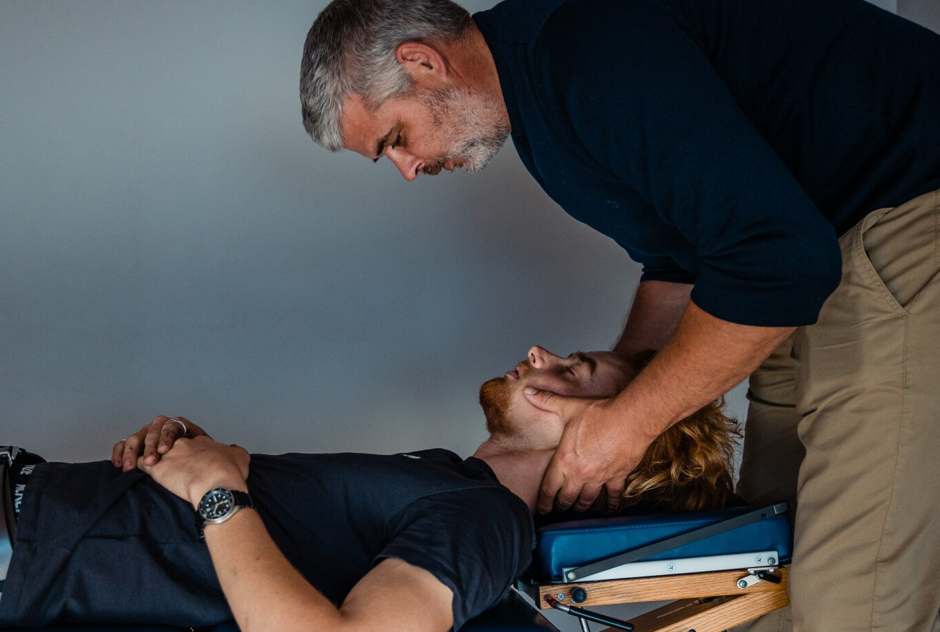 a man is laying on a table getting a neck massage from a doctor .