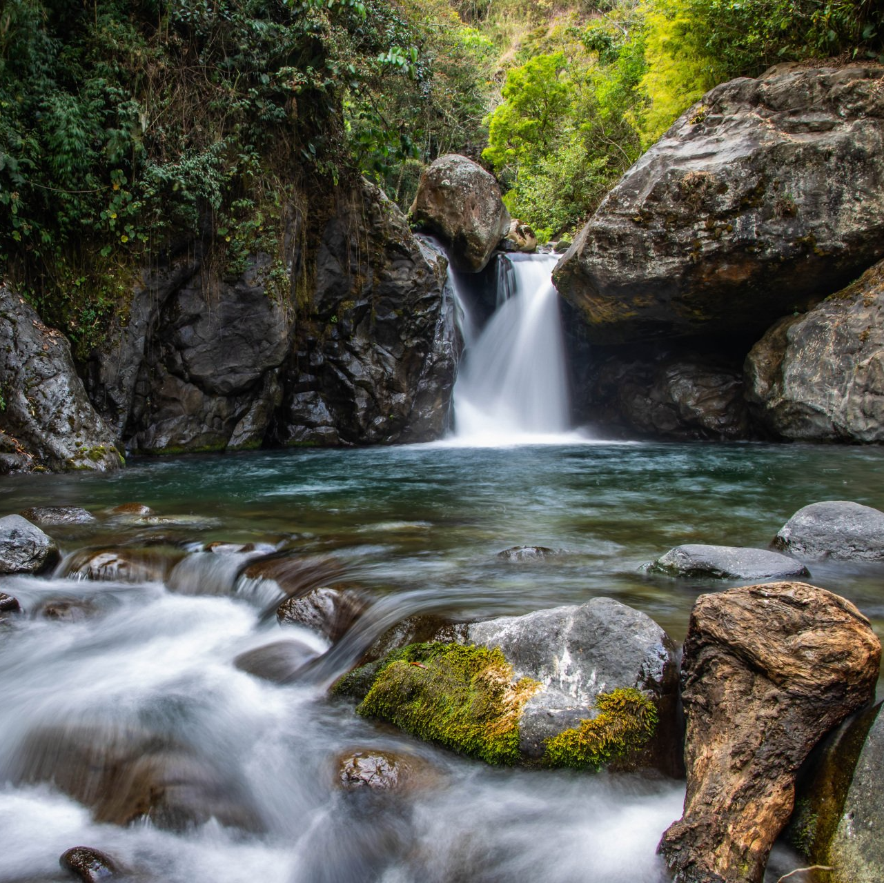 a waterfall is surrounded by rocks and trees