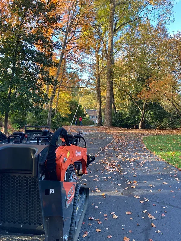 A small orange tractor is parked on the side of a road.