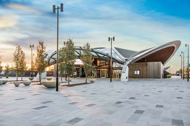A large building with a roof surrounded by trees and street lights.