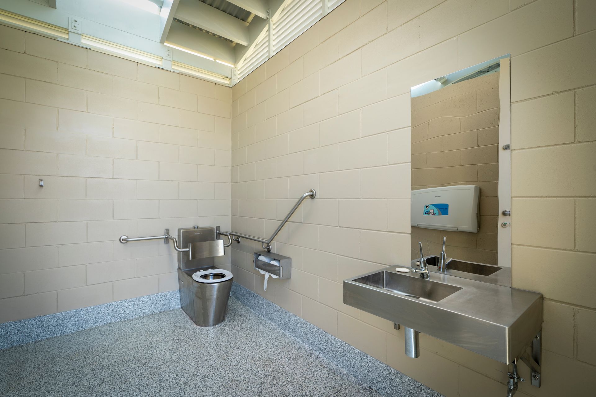 A bathroom with a toilet, sink, and mirror.