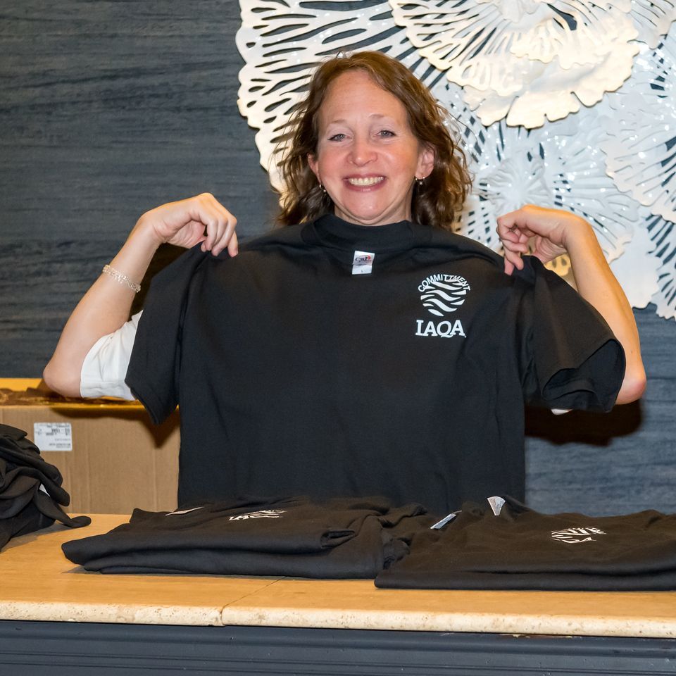 A woman is holding up a black laqa t-shirt