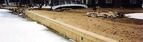 Wooden retaining wall along a shoreline with ice in the water.