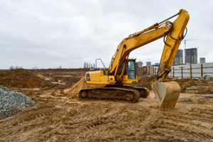 A yellow excavator is moving dirt on a construction site.