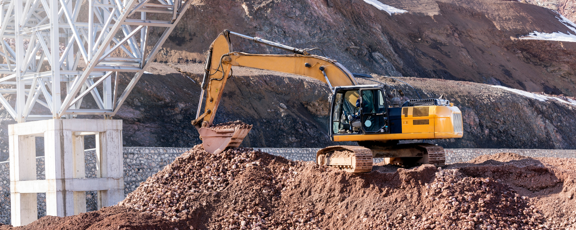 A yellow excavator is digging a pile of dirt on a construction site.