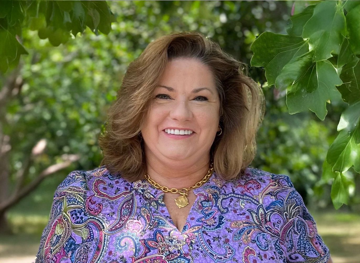 Woman in glasses and blazer taking notes; blurred person on couch.