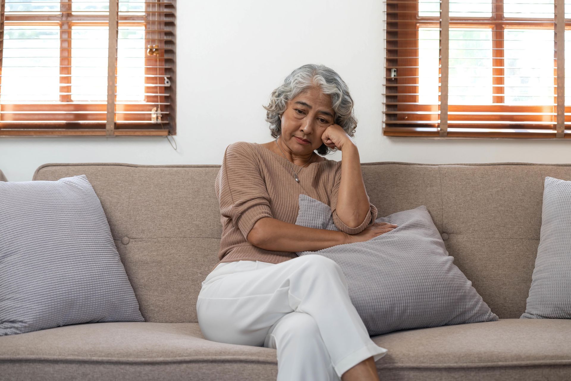 Woman with gray hair, arms crossed, looking up with a thoughtful expression.